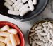 Top view of assorted white and beige capsules in colorful bowls placed on a marble surface.