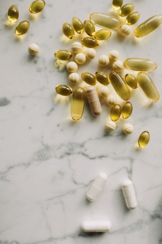 A collection of various pills and supplements displayed on a marble surface.