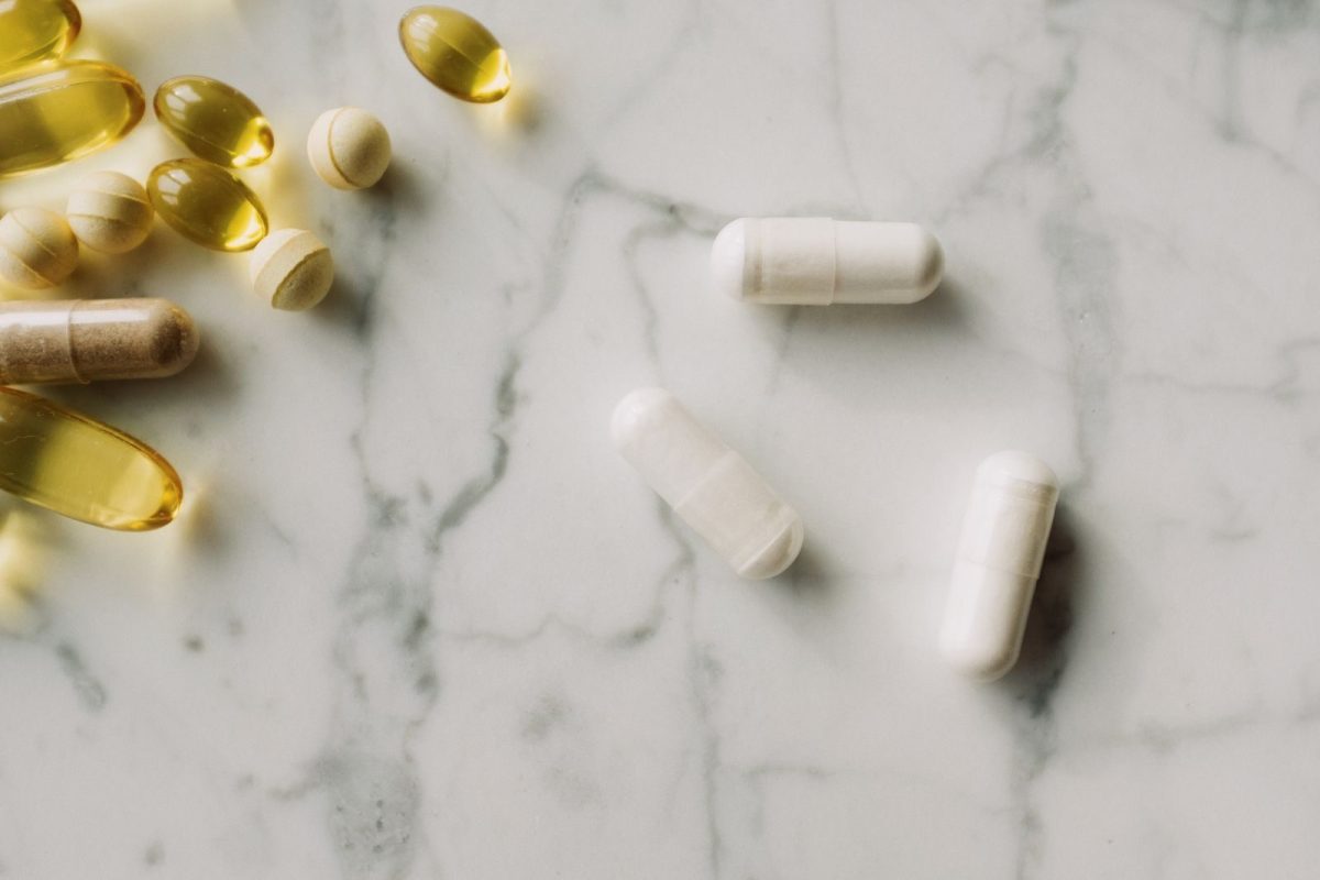 Close-up of various pills and capsules on a marble surface.