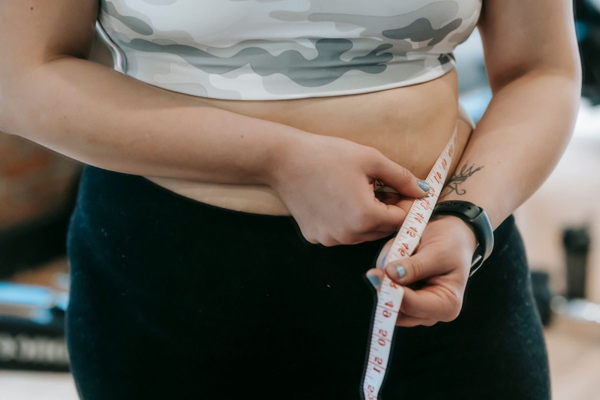 Plus size female with measuring tape measuring waist on blurred background
